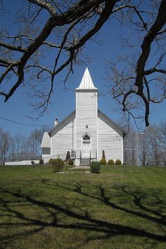 a white church sitting on top of a lush green field