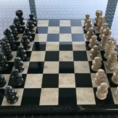 the chess board is made out of marble and has black pieces on each side with white ones