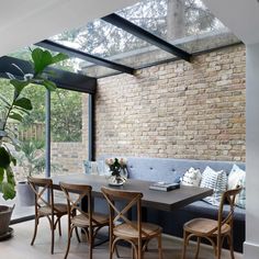 a dining room table with chairs and a bench in front of a brick wall that looks like it has been built into the side of a house