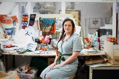 a woman sitting at a desk in an art studio