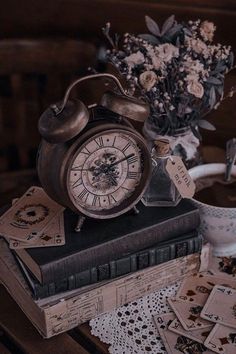 an old fashioned alarm clock sitting on top of a book next to a vase with flowers