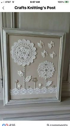 an ornate white frame with flowers and butterflies on the front is sitting on top of a mantle