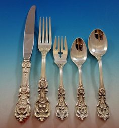 an assortment of silverware including forks, knives and spoons on a blue background