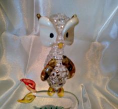 a glass owl figurine sitting on top of a white cloth