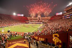 a stadium full of people watching fireworks go off in the sky above them as they watch a football game