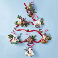 five ornaments are arranged in the shape of a christmas tree with red ribbon and bells