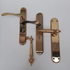 an image of two handles and latches on a white surface that looks like it has been made out of brass