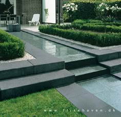 an outdoor garden with steps leading up to the front door and water feature in the middle