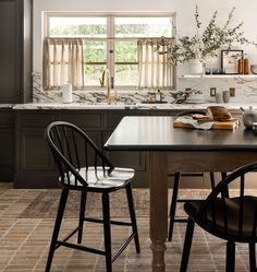 a kitchen with two chairs and a table in front of the window, next to an open book