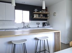 two stools are sitting at the counter in this white and black kitchen with open shelving