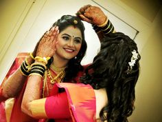 a woman in a red and yellow sari holding her hands up to her face