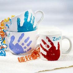 two cups with handprints on them are sitting next to each other in front of colorful beads