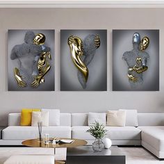 three gold and silver artwork pieces in a living room with couches, tables and coffee table