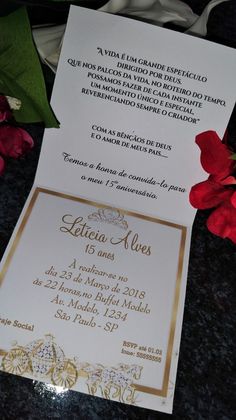 a white and gold wedding card with red flowers on the table in front of it