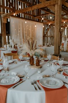 the table is set for an event with orange napkins and white place settings on it