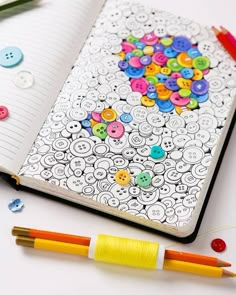 an open notebook with buttons and crayons on it