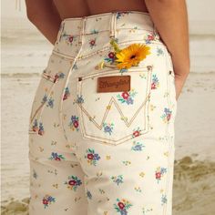 Good Days Start With Good Denim, And You Can't Go Wrong With The She's Cheeky Pant. Serving Up A Hip-Hugging Fit That Can't Be Beat, These White Denim Beauties Take A Timeless 5-Pocket Design And Go Full Flower Power With A Sweet Floral Print. They're High-Waisted, Button Up The Front, And Feature The Iconic Wrangler Stitching On The Back Pockets. To Top It All Off, These Cheeky Wonders Are Made With Eco-Conscious Cotton Denim. Our Eco-Conscious Cotton Is Farmed And Produced In A Way That Aims T White Floral Print Jeans For Spring, Casual White Jeans With Floral Print, White Relaxed Fit Retro Jeans, White Retro Relaxed Fit Jeans, White Retro Jeans With Relaxed Fit, White Retro Jeans For Spring, Retro White Jeans For Spring, White Cotton Jeans With Floral Print, White High-rise Retro Jeans