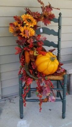 a chair with fall leaves and pumpkins on it sitting in front of a house