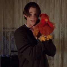 a young man holding a stuffed animal in his right hand and looking at the camera