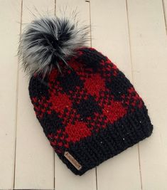 a black and red hat with a grey pom - pom on top of it