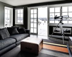 a living room filled with furniture next to windows and a camera on a tripod