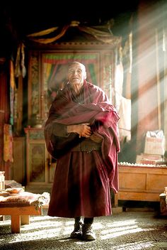 a man standing in a room with sunlight coming through the window and his hands on his chest