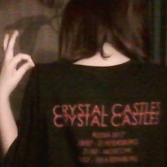 a woman wearing a black shirt with the words crystal castle on it's back