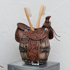 two toothbrushes in a brown leather case on a metal stand with a white wall behind it