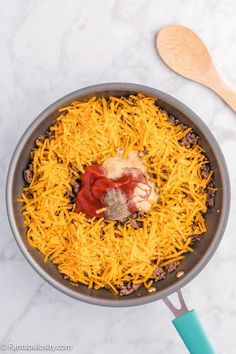 cheese and other ingredients in a skillet on a marble counter top with utensils