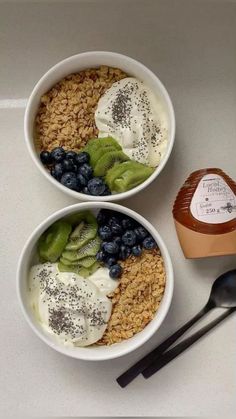 two bowls filled with fruit and yogurt on top of a white countertop