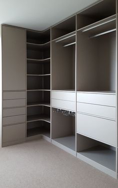 an empty walk in closet with white drawers and gray shelves on the wall, along with carpeted flooring