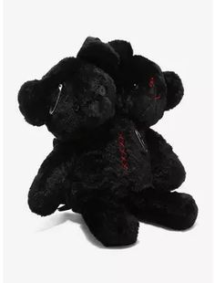 two black teddy bears sitting next to each other on a white surface with red writing