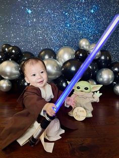 a baby in a star wars costume is holding a lightsaben and smiling at the camera