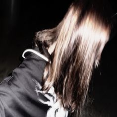 a person with long hair standing in the dark