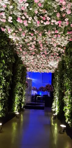 the inside of a flower covered walkway with lights and flowers all over it's walls