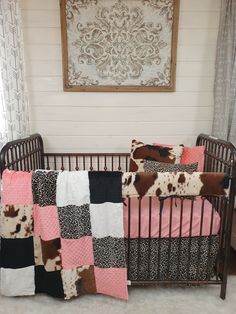 a baby crib with pink, black and white quilts