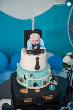 a baby in a suit case on top of a cake with blue and white decorations