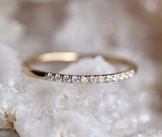 a yellow gold wedding band with five diamonds on top of some white rocks and crystals