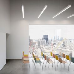 there are many chairs in this room with the city view out the window behind them