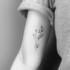 a black and white photo of a woman's arm with a flower tattoo on it