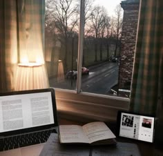 an open book sitting on top of a desk next to a laptop computer and lamp