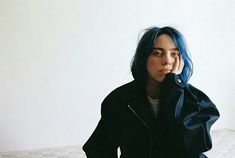 a woman with blue hair sitting on a bed