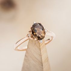 a close up of a ring on top of a wooden stand with a brown diamond