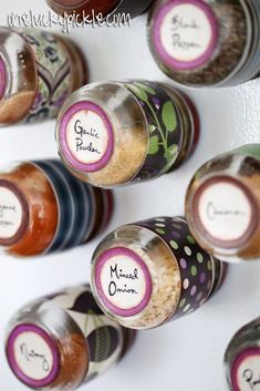 spice jars with labels on them are lined up against a wall in a kitchen or dining room