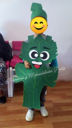 a child wearing a costume made to look like a leaf with a smiley face on it