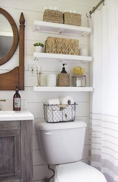 a white toilet sitting in a bathroom next to a wooden cabinet and shower curtain with wicker baskets on it