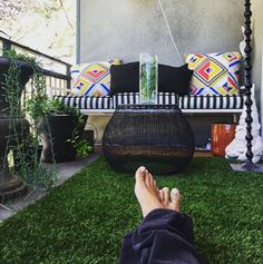 a person laying in the grass with their feet up on a swing bed that is attached to a wall