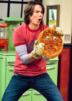 a man holding up a pizza with googly eyes