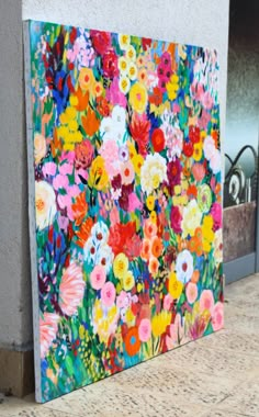 a painting on the side of a building that has flowers painted on it and is next to a wall