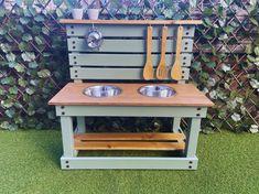 an outdoor kitchen made out of pallets with two bowls and spoons on it